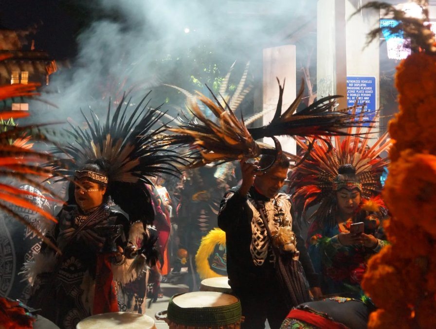 Danza azteca dancers in feathered headdresses surrounded by copal smoke at night