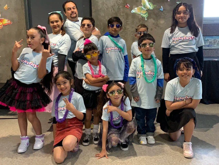 Group of kids in matching Jóvenes t-shirts and sunglasses posing together